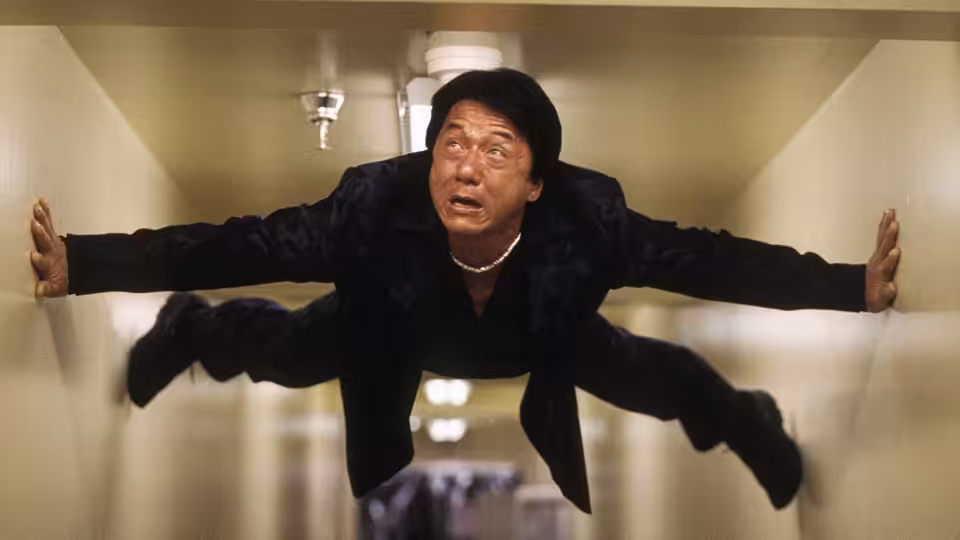Jackie Chan as Lee braces himself across a narrow corridor
