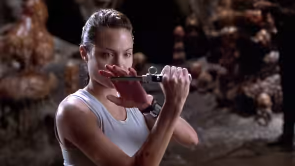 Lara Croft (Angelina Jolie) examines a small metal device inside a rocky cavern