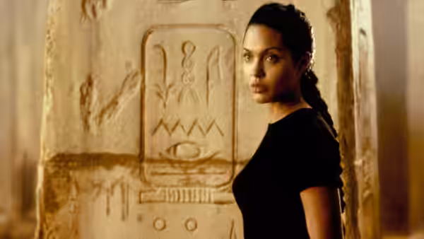 Lara Croft (Angelina Jolie) stands beside an ancient wall covered in hieroglyphs
