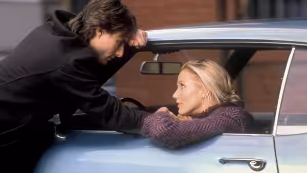 David Aames (Tom Cruise) leans over a convertible as Julie Gianni (Cameron Diaz) sits inside