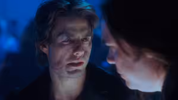 David Aames (Tom Cruise), his face scarred, looks toward another man in blue light