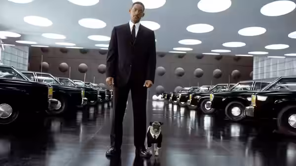 Jay (Will Smith) stands with Frank the pug between rows of black cars
