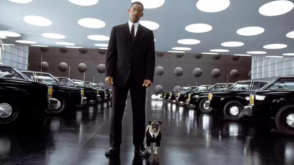 Jay (Will Smith) stands with Frank the pug between rows of black cars