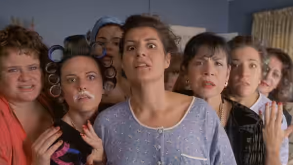 Toula Portokalos (Nia Vardalos) stands wide-eyed among bridesmaids in hair rollers
