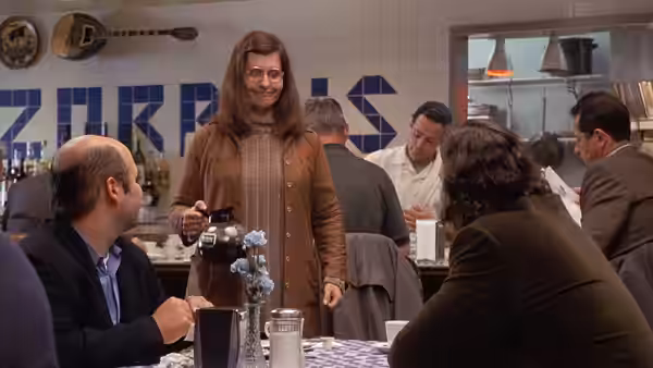 Ian Miller (John Corbett) sits with Toula's family as she serves coffee at the restaurant