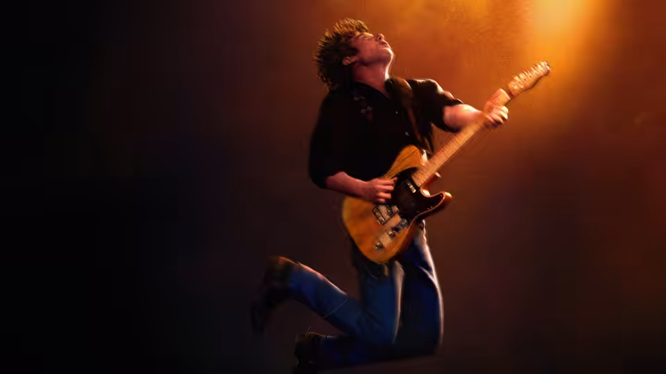 Jeremy Allen White as Bruce Springsteen jumps while playing electric guitar onstage