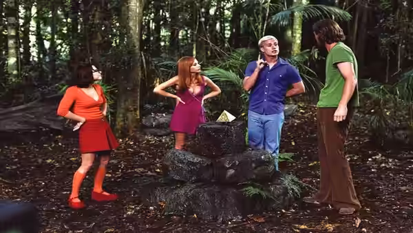 Velma, Daphne, Fred, and Shaggy gather around a stone fountain in the jungle