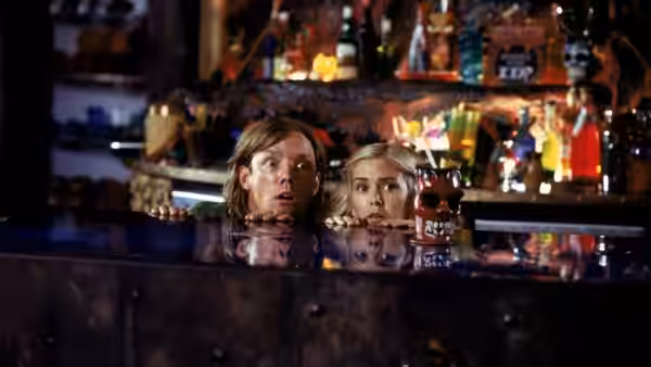 Shaggy (Matthew Lillard) and Mary Jane (Isla Fisher) peer over a bar counter