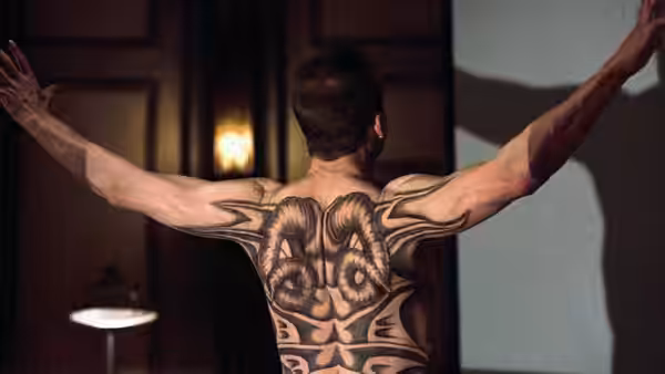 Francis Dolarhyde (Ralph Fiennes) spreads his arms, revealing an elaborate tattoo across his back