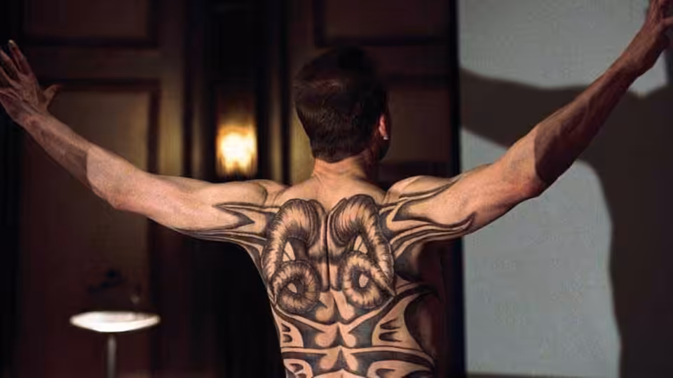 Francis Dolarhyde (Ralph Fiennes) spreads his arms, revealing an elaborate tattoo across his back
