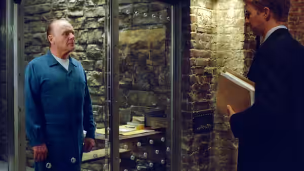 Hannibal Lecter (Anthony Hopkins) stands inside his glass cell as Will Graham visits
