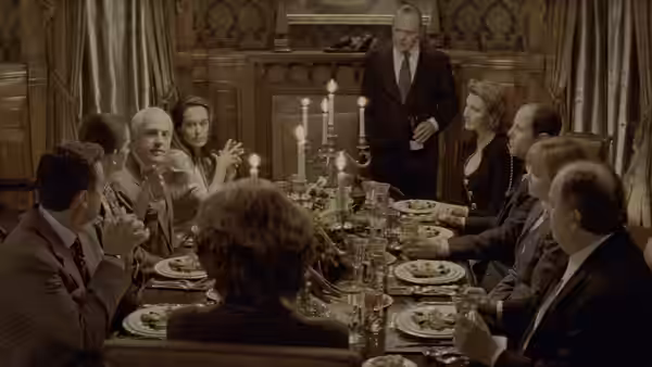 Hannibal Lecter (Anthony Hopkins) stands beside a candlelit dining table as guests applaud