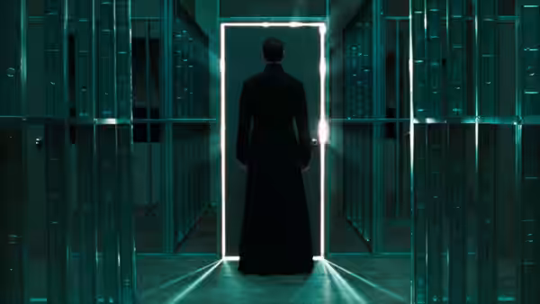 A long-coated figure faces a glowing doorway in a corridor of glass
