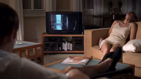 Anna (Susanne Lothar) reclines on a sofa while watching television in the living room