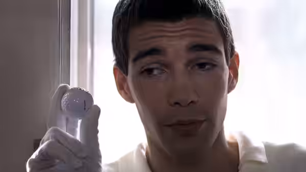 Paul (Arno Frisch) holds up a bloodied white glove while looking to the side
