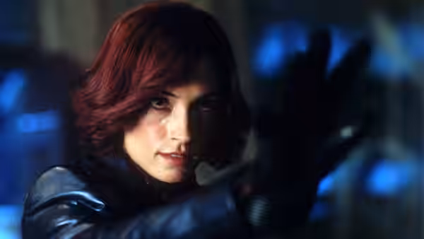 Jean Grey (Famke Janssen) raises a gloved hand in a dim blue-lit room