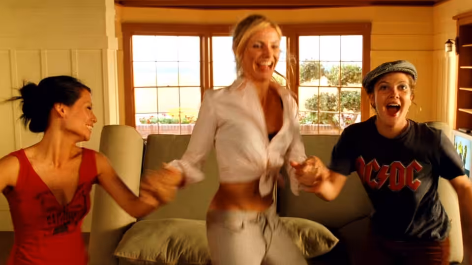 Alex Munday (Lucy Liu) and Natalie Cook (Cameron Diaz) dance with a young man indoors