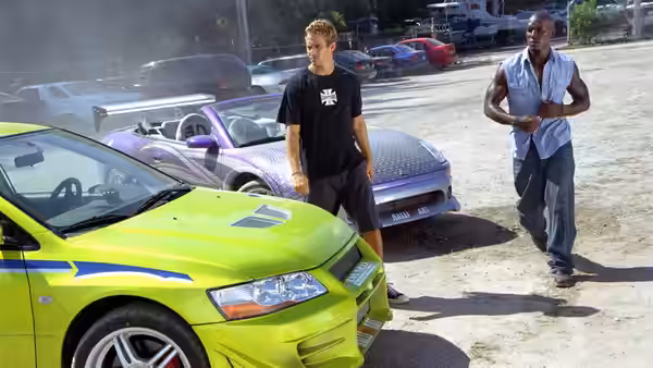 Brian O'Conner (Paul Walker) and Roman Pearce (Tyrese Gibson) stand beside brightly colored cars