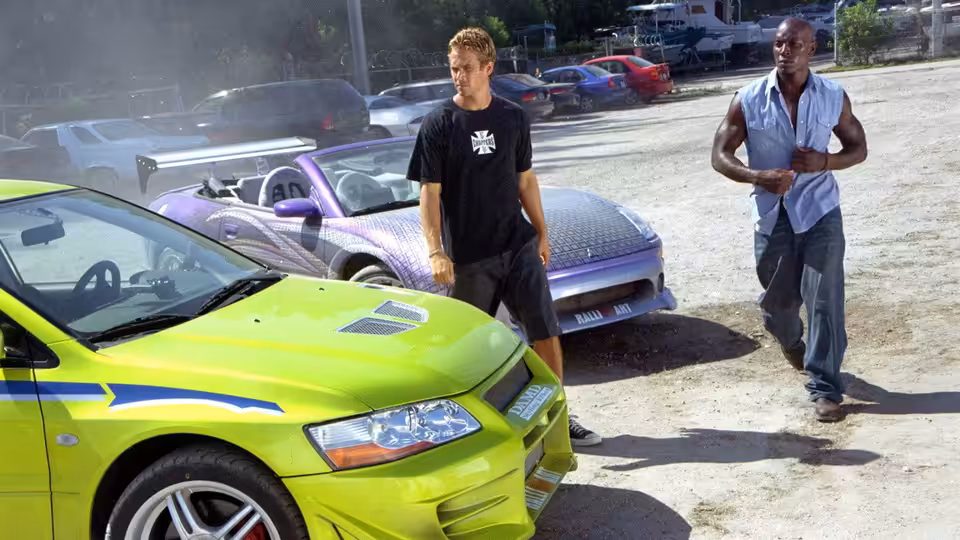 Brian O'Conner (Paul Walker) and Roman Pearce (Tyrese Gibson) stand beside brightly colored cars