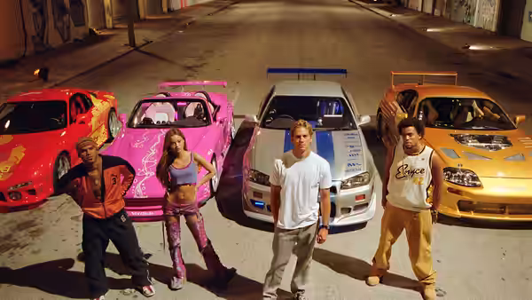 Brian O'Conner (Paul Walker) and Roman Pearce (Tyrese Gibson) stand before a lineup of street racers and cars
