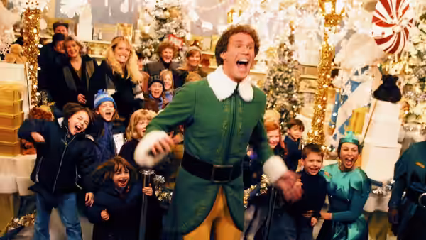 Buddy (Will Ferrell) celebrates among children in a festively decorated department store