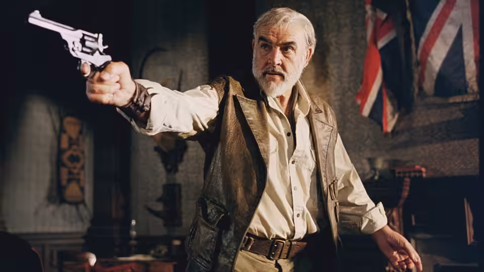 Allan Quatermain (Sean Connery) aims a revolver inside a room