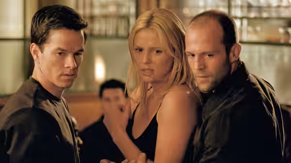 Charlie Croker, Stella Bridger and Handsome Rob watch something offscreen in a crowded room