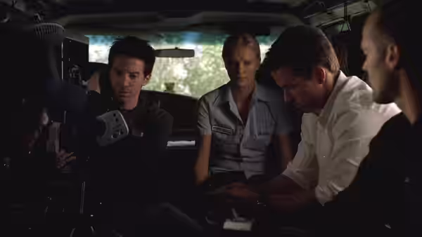 Charlie Croker and his crew gather inside a vehicle, examining equipment
