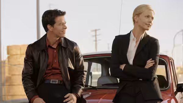 Charlie Croker (Mark Wahlberg) and Stella Bridger (Charlize Theron) stand beside a red car