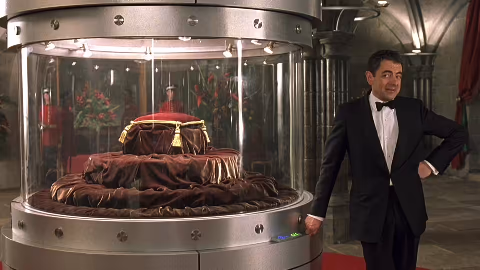 Johnny English (Rowan Atkinson) stands beside a ceremonial crown displayed inside a glass case