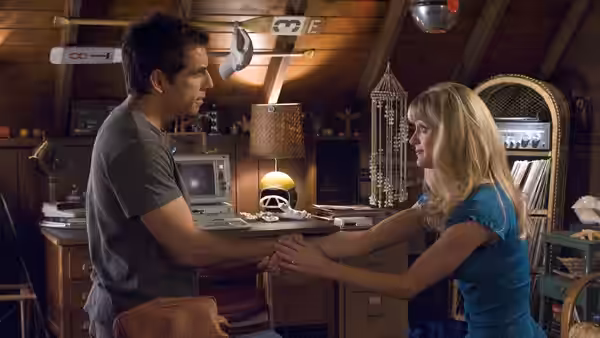 Greg and Pam hold hands in a wood-paneled kitchen