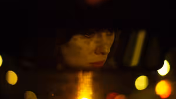 Scarlett Johansson looking to the side inside a car with bokeh lights