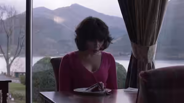 Scarlett Johansson in a pink top at a table overlooking a lake