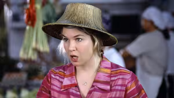 Bridget Jones (Renée Zellweger) speaks in a wide-brimmed hat inside a kitchen