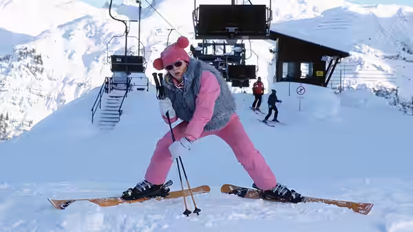 Bridget Jones (Renée Zellweger) poses on skis in pink clothes outside a snowy mountain lodge