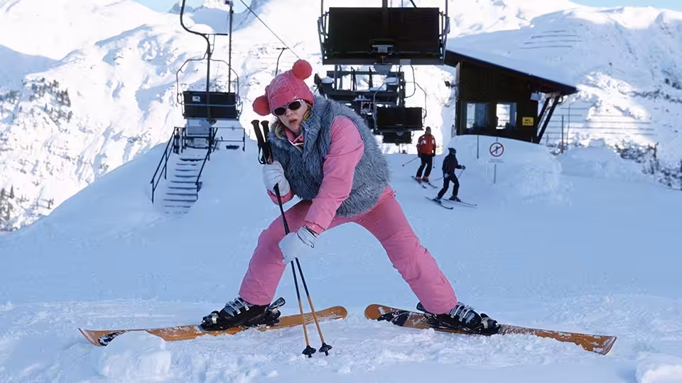Bridget Jones (Renée Zellweger) poses on skis in pink clothes outside a snowy mountain lodge