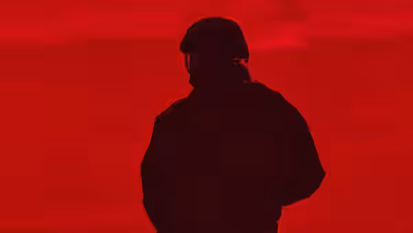 A soldier in helmet silhouetted against a red sky