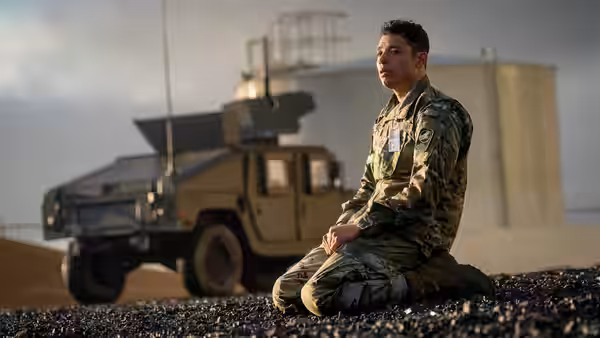 Major Daniel Gonzalez (Anthony Ramos) kneeling beside a military vehicle