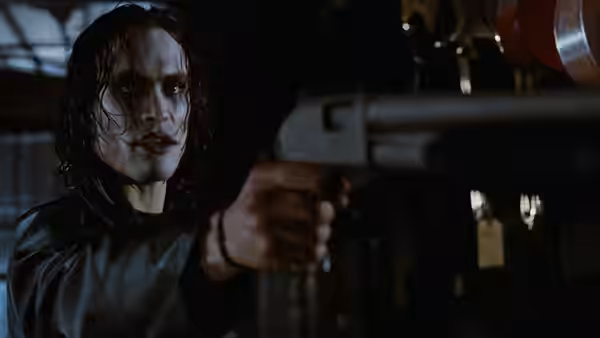 Eric (Brandon Lee) aims a handgun inside a dim industrial room