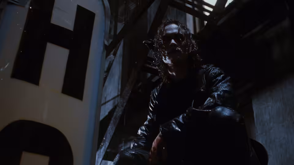 Eric (Brandon Lee) crouches on a metal structure above a dark building interior