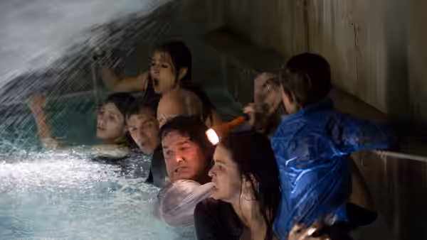 Passengers struggle through rushing water inside the ship, gripping the corridor walls