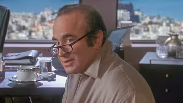Gus Klein (Bob Hoskins) looks over his glasses while seated at a table