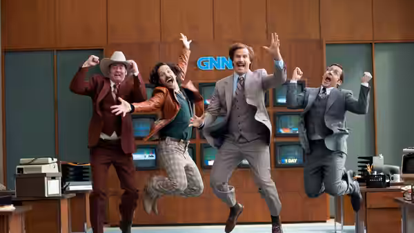 Ron Burgundy (Will Ferrell) and fellow newsmen leap in front of the GNN newsroom screens