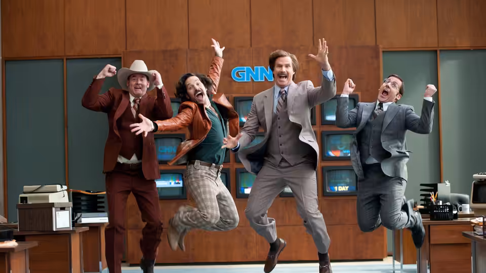 Ron Burgundy (Will Ferrell) and fellow newsmen leap in front of the GNN newsroom screens