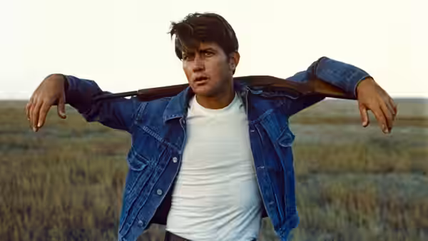Kit (Martin Sheen) with arms spread wide in a grassy field