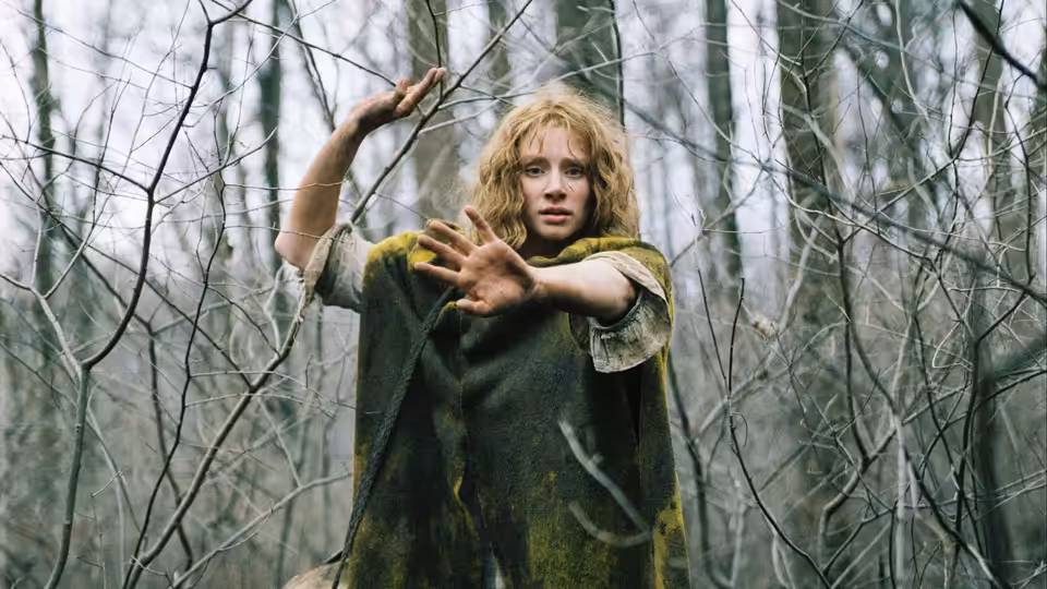Noah Percy (Adrien Brody) raises his hands among bare trees in the forest