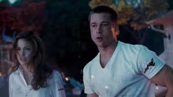 Jane Smith (Angelina Jolie) and John Smith (Brad Pitt), wounded in bloodstained shirts, stand outdoors at night