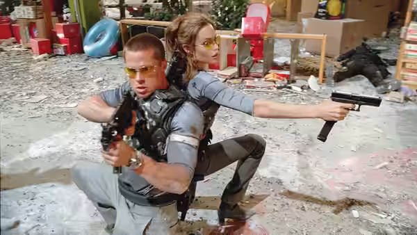 John Smith (Brad Pitt) and Jane Smith (Angelina Jolie) take cover back-to-back, aiming guns amid rubble