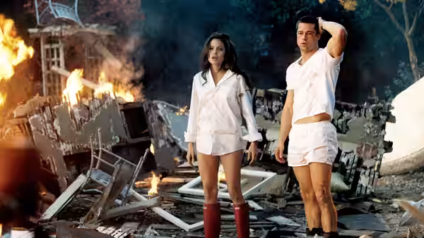 Jane Smith (Angelina Jolie) and John Smith (Brad Pitt) stand amid the burning wreckage of their home