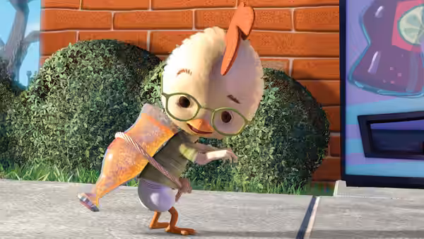 A bespectacled, fluffy creature balances on one leg while carrying an orange traffic cone